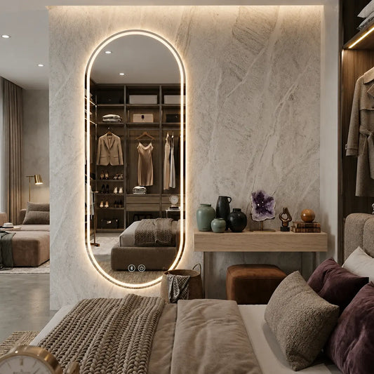 Luxury full-length oval standing LED mirror with warm ambient backlighting in a modern minimalist bedroom dressing area layout
