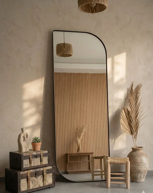 Large floor mirror in a room with decorative items and natural light