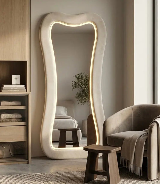 A large full-length curved LED floor mirror featuring a thick plush cream textured frame with a wavy inner illuminated neon glow border,