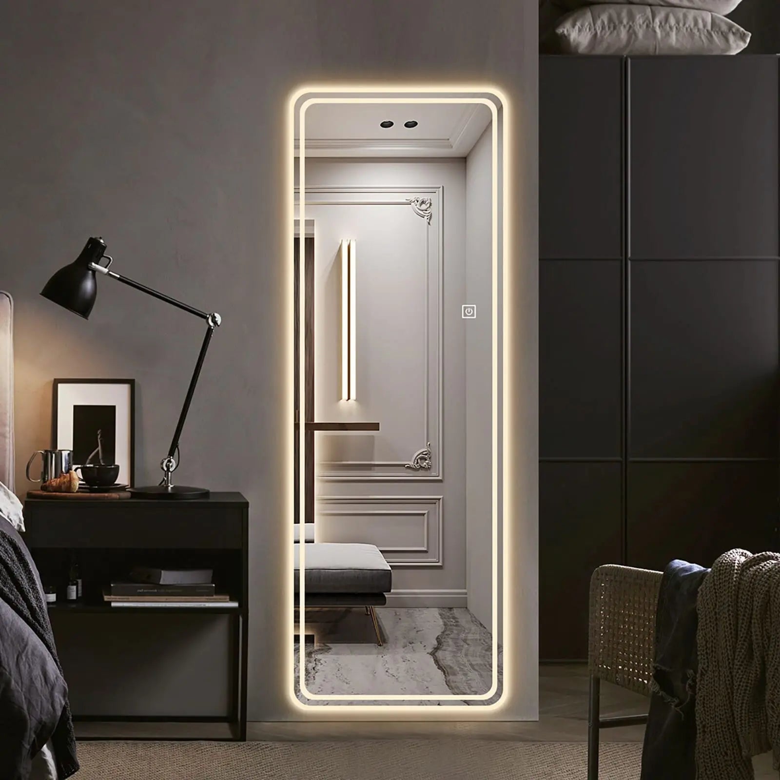 Modern bedroom with a large illuminated floor mirror, dark furniture, and decorative elements.