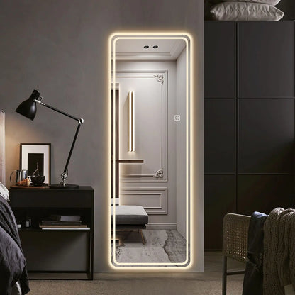 Modern bedroom with a large illuminated floor mirror, dark furniture, and decorative elements.