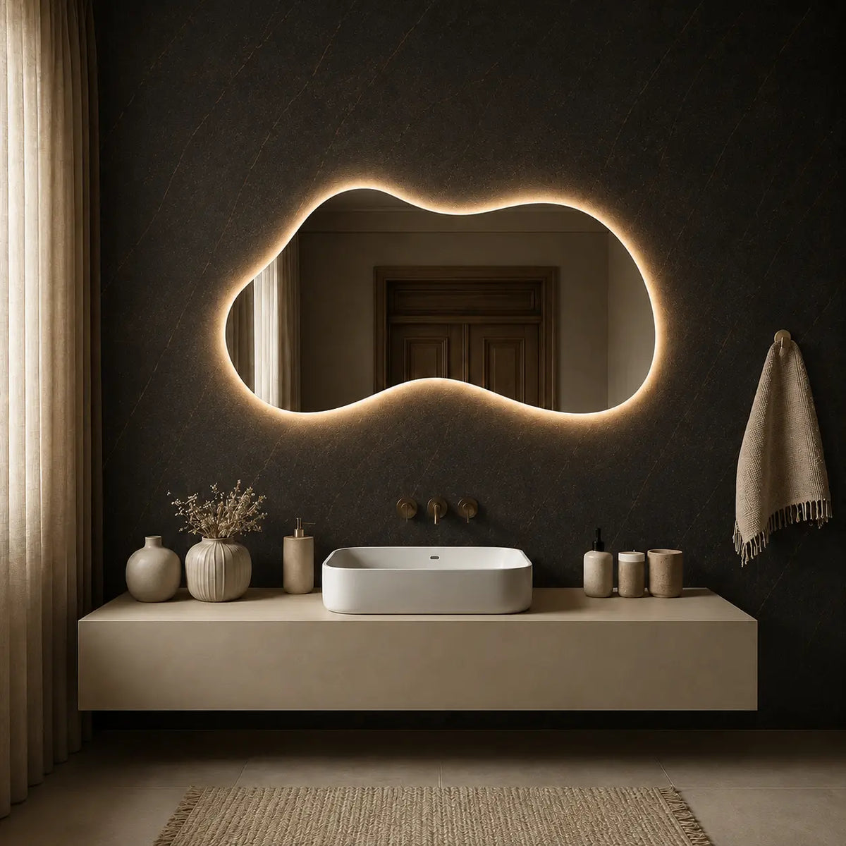 Asymmetrical LED mirror with soft backlit lighting installed above a modern bathroom vanity.