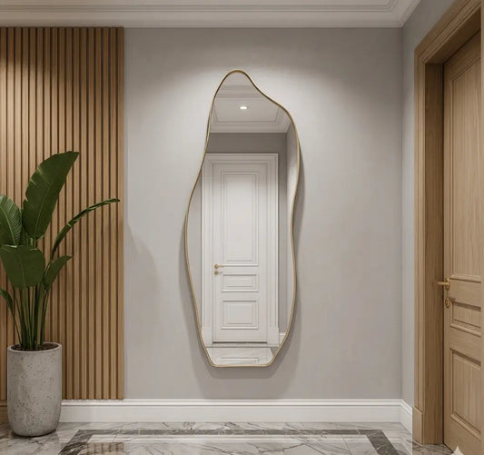 Full-length asymmetrical wall mirror with a sleek thin gold frame, mounted in a modern minimalist entryway hallway
