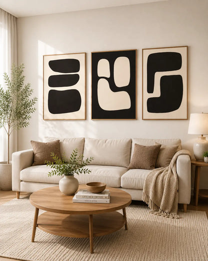 Minimalist wall art set of 3 with black abstract shapes above a modern sofas