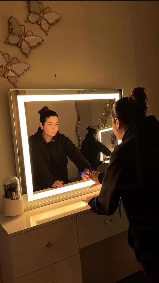 woman using led dressing mirror with vanity lights above white dressing table